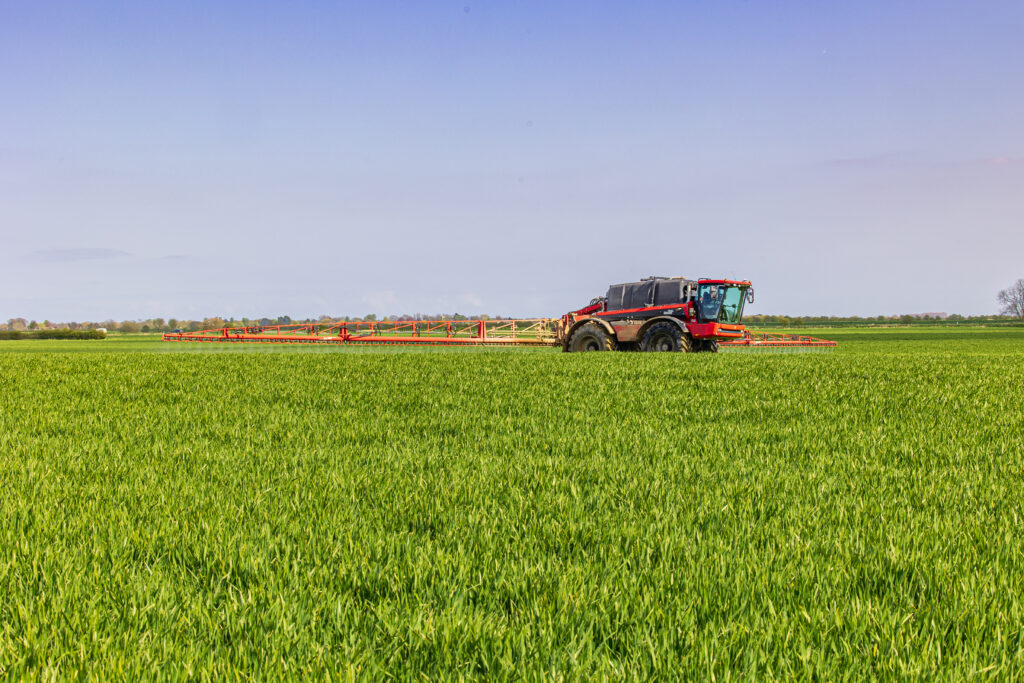 Crop sprayer applying folia products to wheat